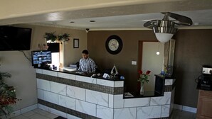 A reception desk with a flat-screen TV, a clock, and a ceiling fan. - Executive Inn (Snyder)