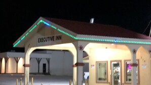 A building with a sign reading "EXECUTIVE INN" and a covered area with a red roof. - Executive Inn (Snyder)