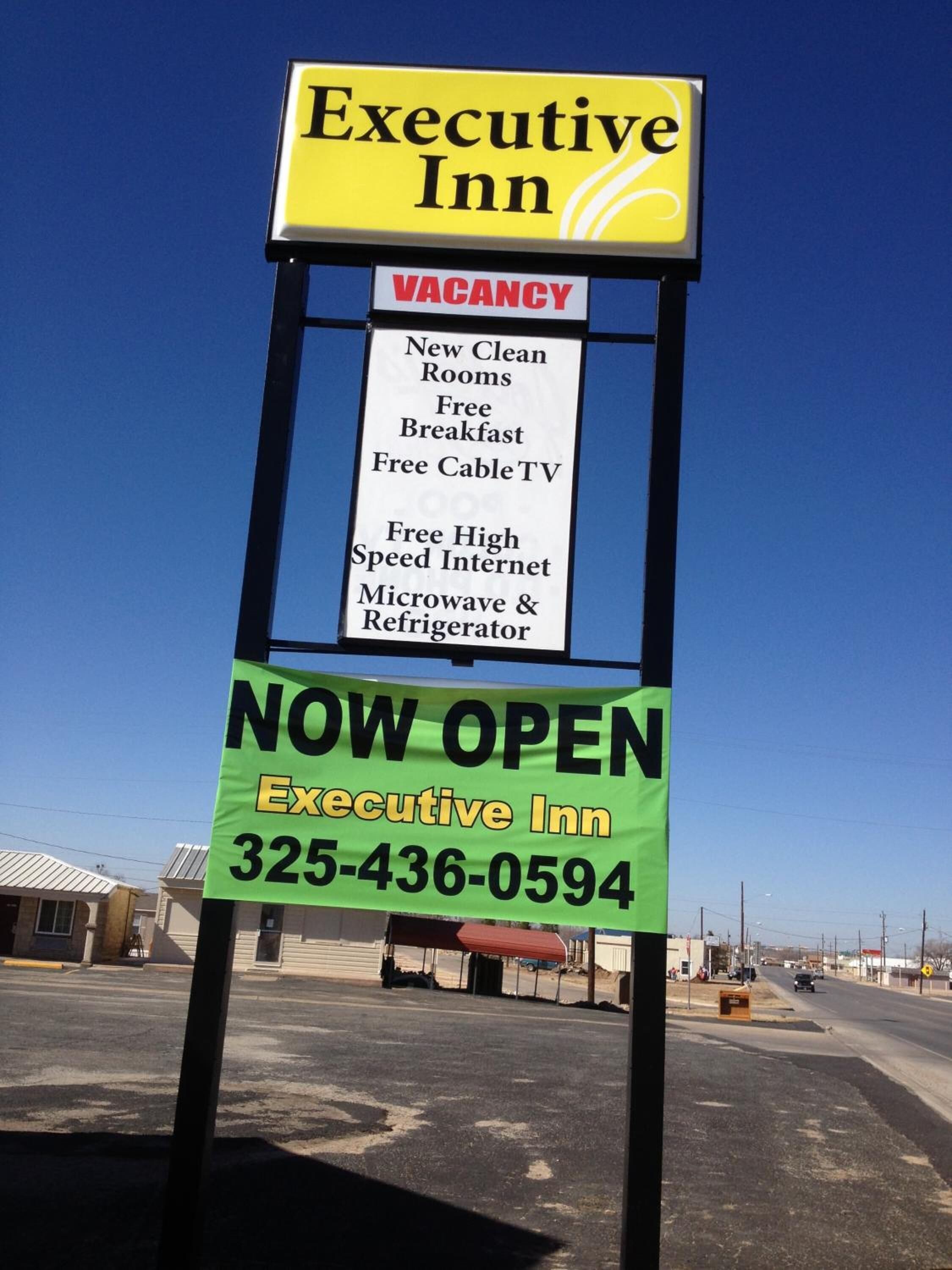 A sign for the Executive Inn advertising a vacancy, new clean rooms, free breakfast, free cable TV, high-speed internet, and microwave & refrigerator.