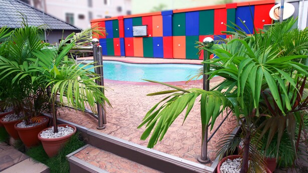 A pool area with colorful walls, potted plants, and a clear blue pool. - Western Dreams Hotel (Abuja)