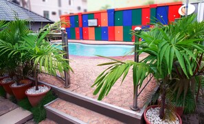 A pool area with colorful walls, potted plants, and a clear blue pool. - Western Dreams Hotel (Abuja)