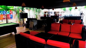 A pool table, red sofas, and a billiards table in a room with a view of a street and greenery. - Western Dreams Hotel (Abuja)