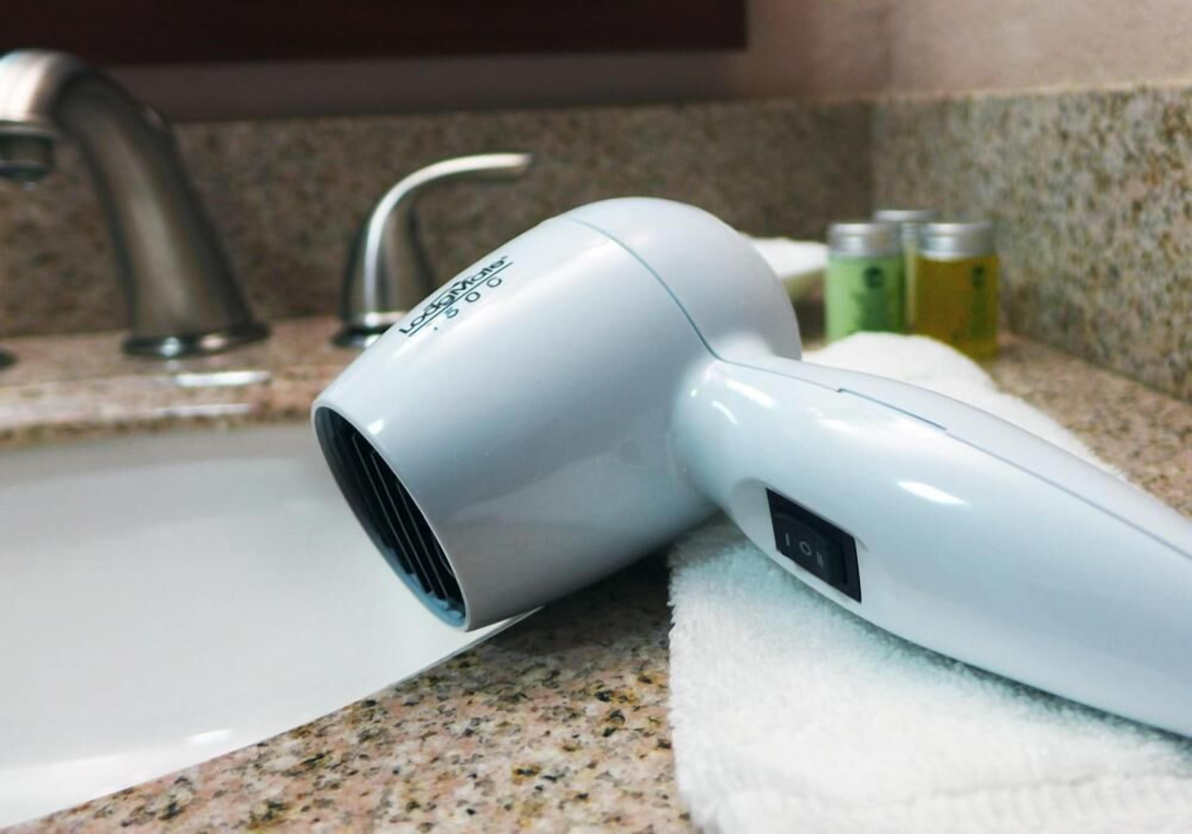 A hair dryer on a granite countertop near a sink.
