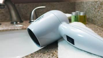 A hair dryer on a granite countertop near a sink.