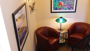A room with two leather armchairs, a small table with a lamp, a framed picture on the wall, and a staircase. - Waterfront Hotel and Marina (McHenry)