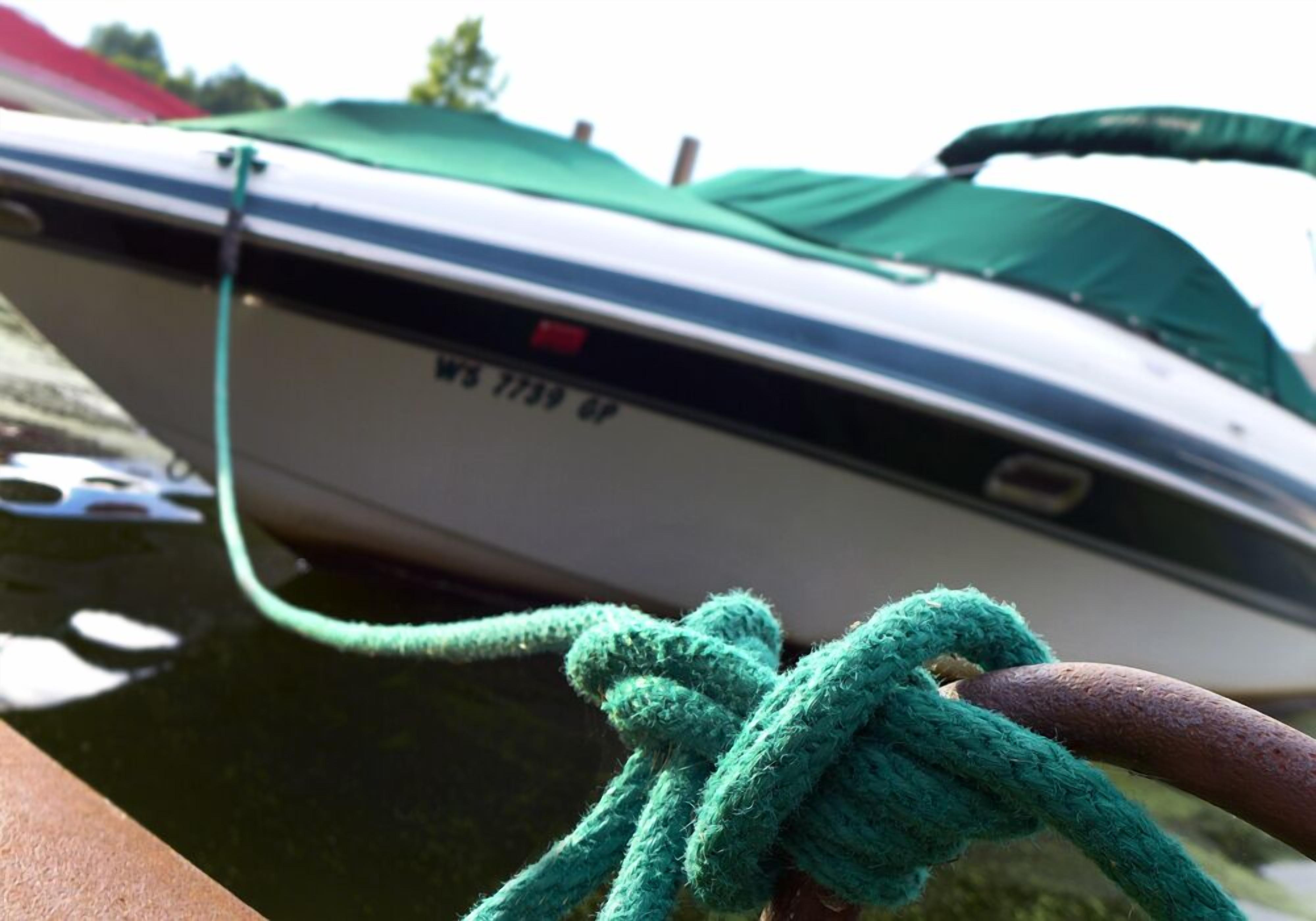 A boat tied to a dock with a green rope.