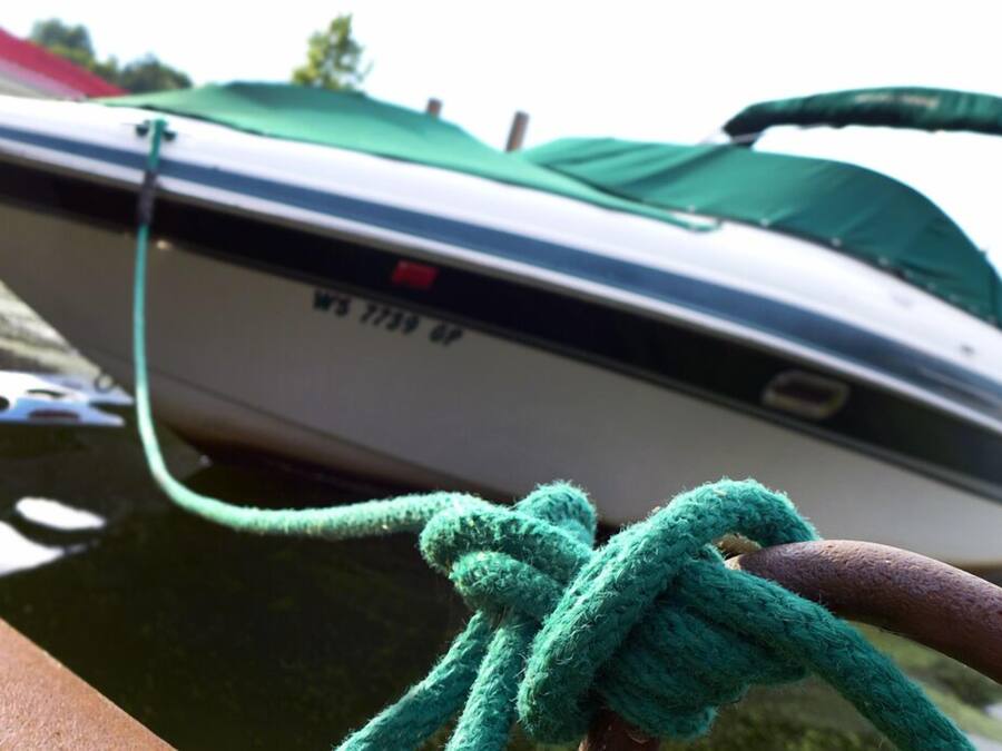 A boat tied to a dock with a green rope.