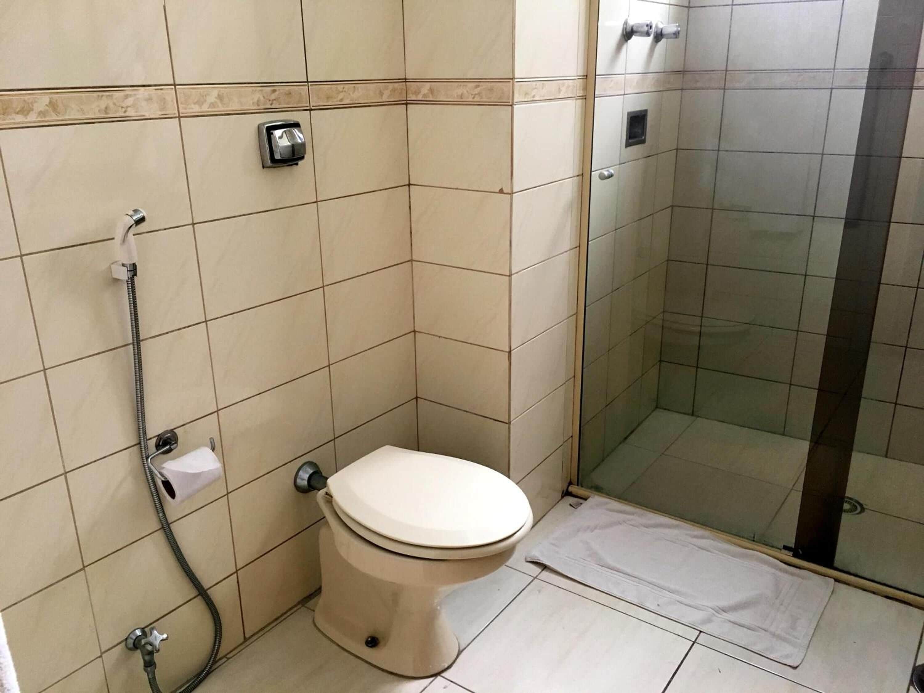 Et badeværelse med toilet, brusebad og et brusekabine med glasvægge.