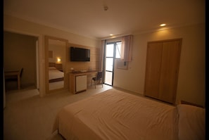 Ein Hotelzimmer mit einem Bett, einem Schreibtisch, einem Sessel, einem Fernseher und einem Kleiderschrank.