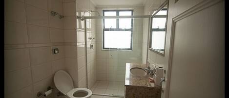 A bathroom with a toilet, sink, and shower area.