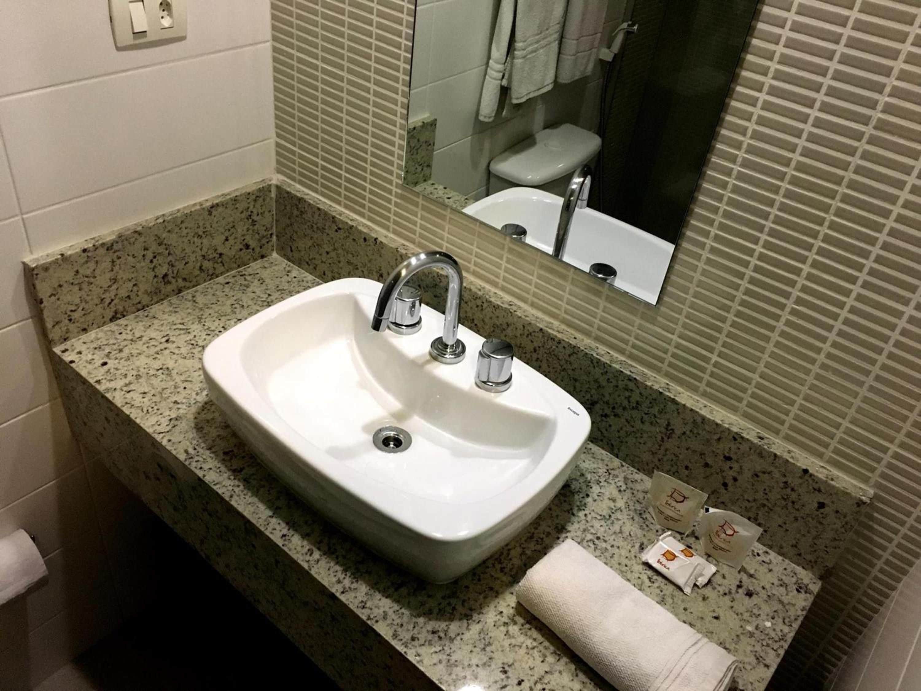 A bathroom with a white sink, a mirror, and a towel on the counter.