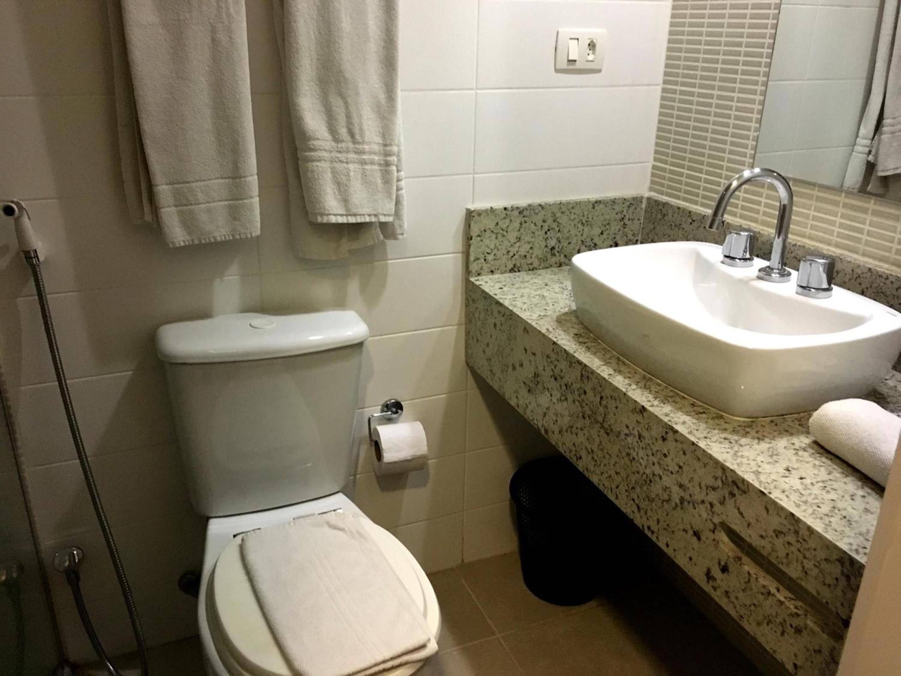 Un bagno con servizi igienici, lavandino e porta asciugamani.