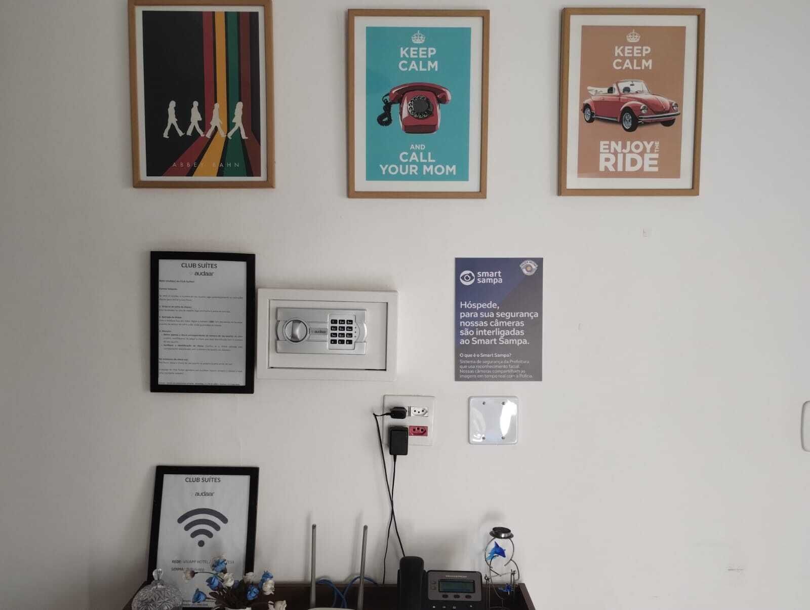 Framed posters, a security keypad, a Wi-Fi symbol, and a thermostat on a wall.