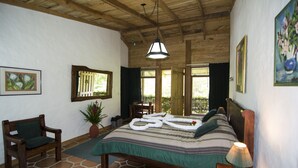A room with a bed, a chair, a table, and a potted plant.
