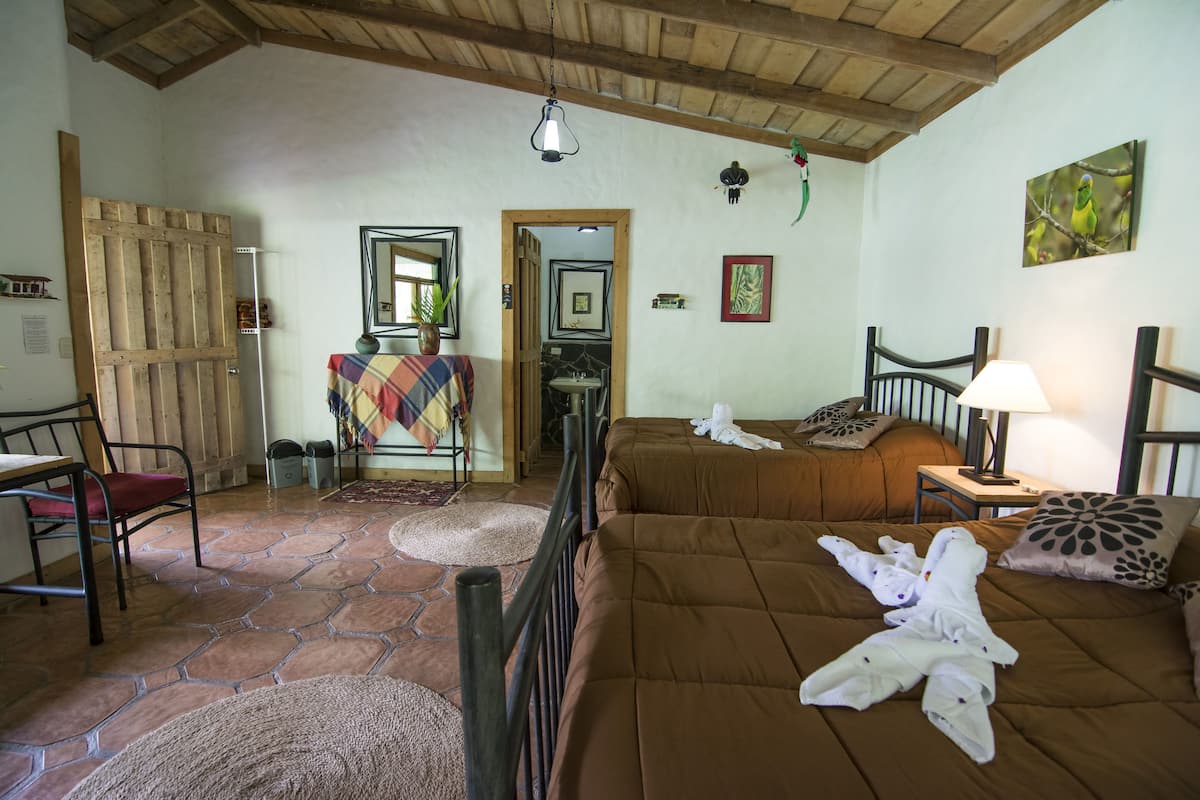 A cozy room with a bed, a chair, a table, and a door.