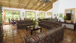 A spacious living room with large windows, a fireplace, and a dining area with chairs and a table.
