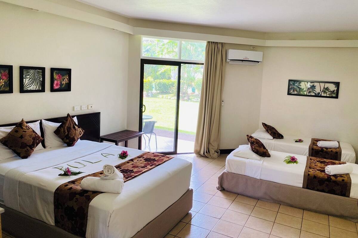 Une chambre d’hôtel avec deux lits, une petite table et une vue sur l’extérieur.