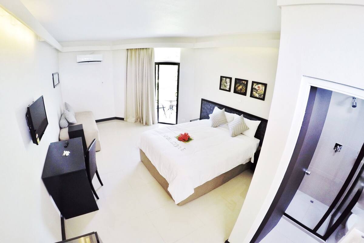 Une chambre d’hôtel avec un lit, un bureau, une chaise, une télévision et une porte.