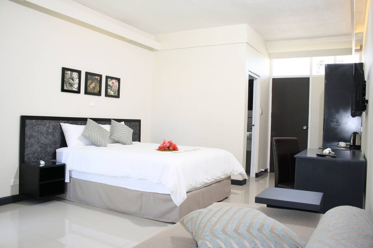 Une chambre d’hôtel moderne équipée d’un lit, de tables de chevet, d’un bureau et d’une chaise.