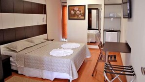 Een slaapkamer met een bed, een bureau, een stoel, een televisie en een schilderij aan de muur.