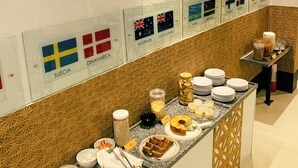 Een buffet met diverse gerechten en een muur waarop de vlaggen van Zweden, Denemarken, Australië en Nieuw-Zeeland staan.
