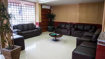 Amplia sala de estar con dos sofás de cuero, una mesa de centro y plantas en macetas.