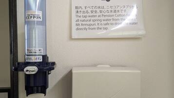 Een bekerdispenser aan de muur en een bord met instructies in zowel Japans als Engels.