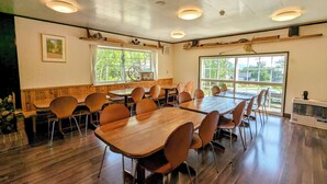A conference room with wooden tables and chairs, large windows, and ceiling lights. - Pension Cotton Farm (Niseko)