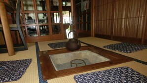 Een kamer met tatami matten, een centraal gelegen haardvuur, houten schuifdeuren en een traditionele Japanse theeset.