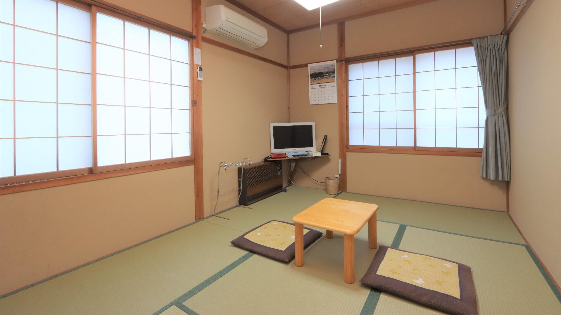 Une pièce de style japonais traditionnel, avec un sol recouvert de tatamis, une télévision et une petite table.