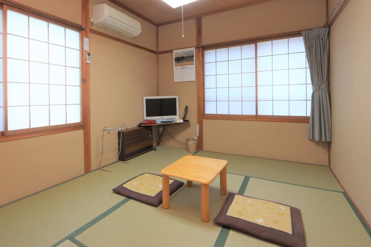 Une pièce de style japonais traditionnel, avec un sol recouvert de tatamis, une télévision et une petite table.