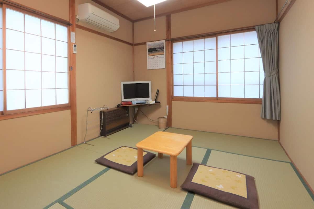 Une pièce de style japonais traditionnel, avec un sol recouvert de tatamis, une télévision et une petite table.