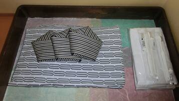 A tray with striped pillows, a patterned blanket, and a package of toiletries.