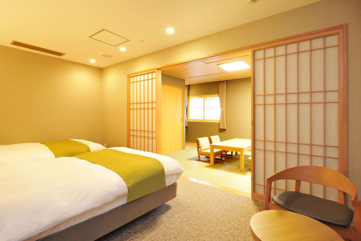 A hotel room with two beds, a dining table, and a chair.