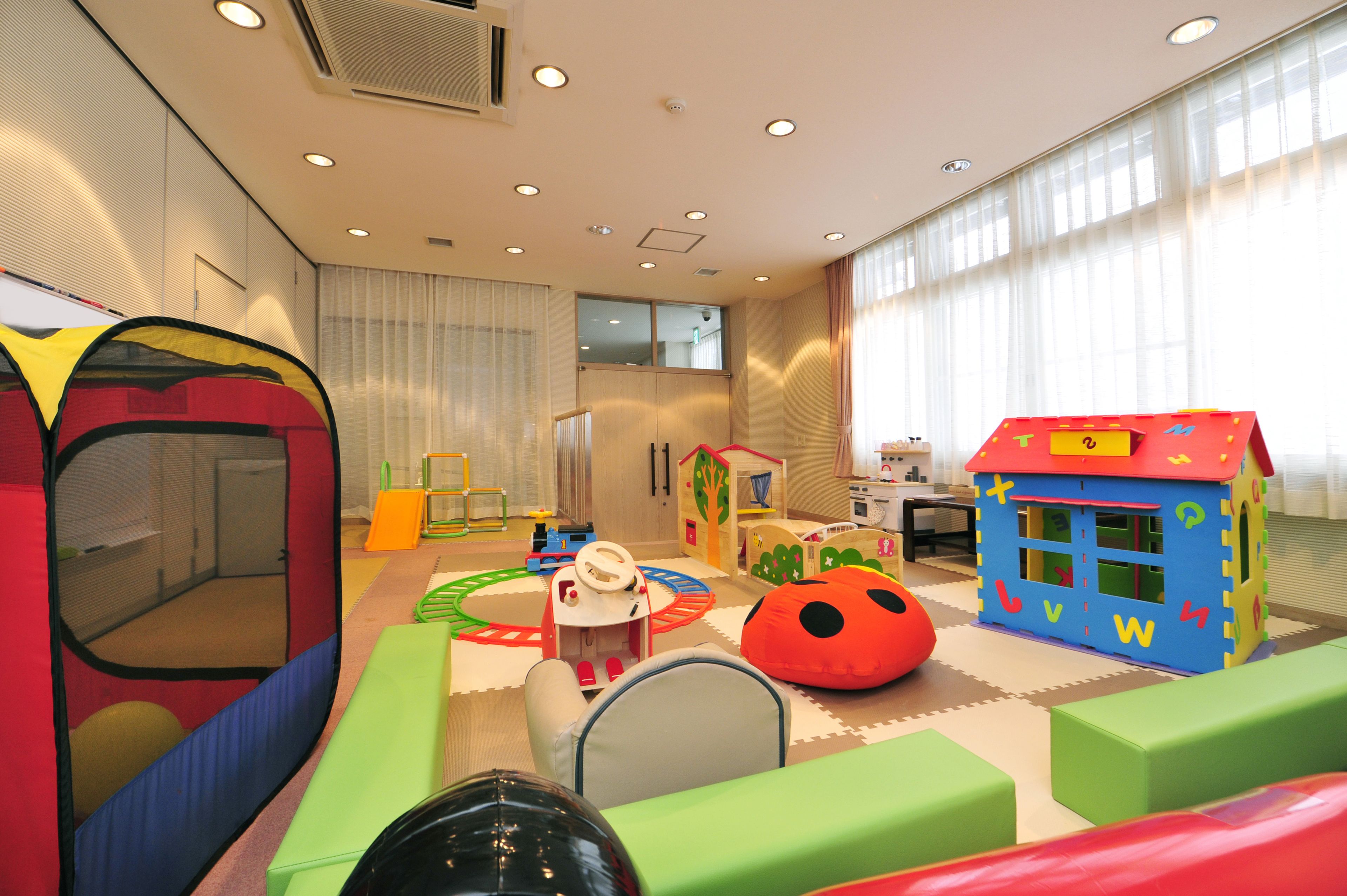 Espaço infantil com trampolim, casinha de brincar e assentos confortáveis.