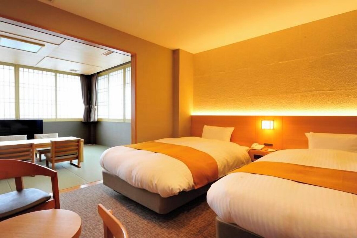 Habitación de hotel con dos camas, un escritorio y una silla.