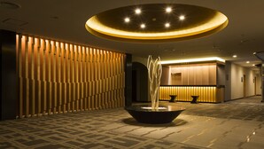 Een moderne lobby met een kamerbreed tapijt met een patroon, een fontein in het midden en een receptiebalie met een warm verlicht ontwerp.