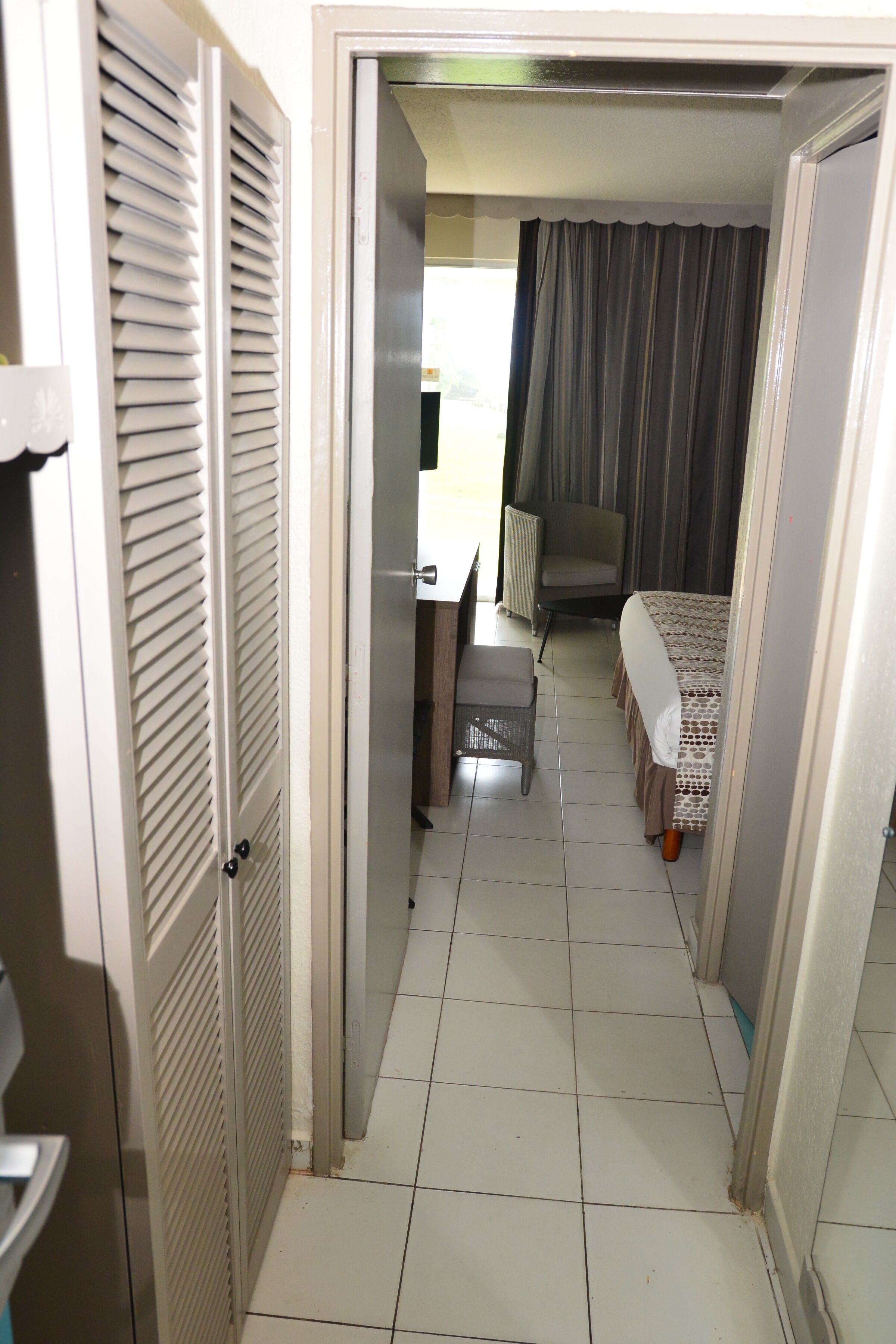 Una habitación de hotel con una cama, una silla, un escritorio y una ventana con cortinas.