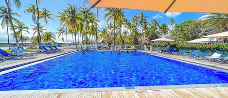 A swimming pool with lounge chairs and palm trees.