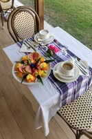 A table set with a white tablecloth, a plate of fruit, a cup of coffee, and a fork.