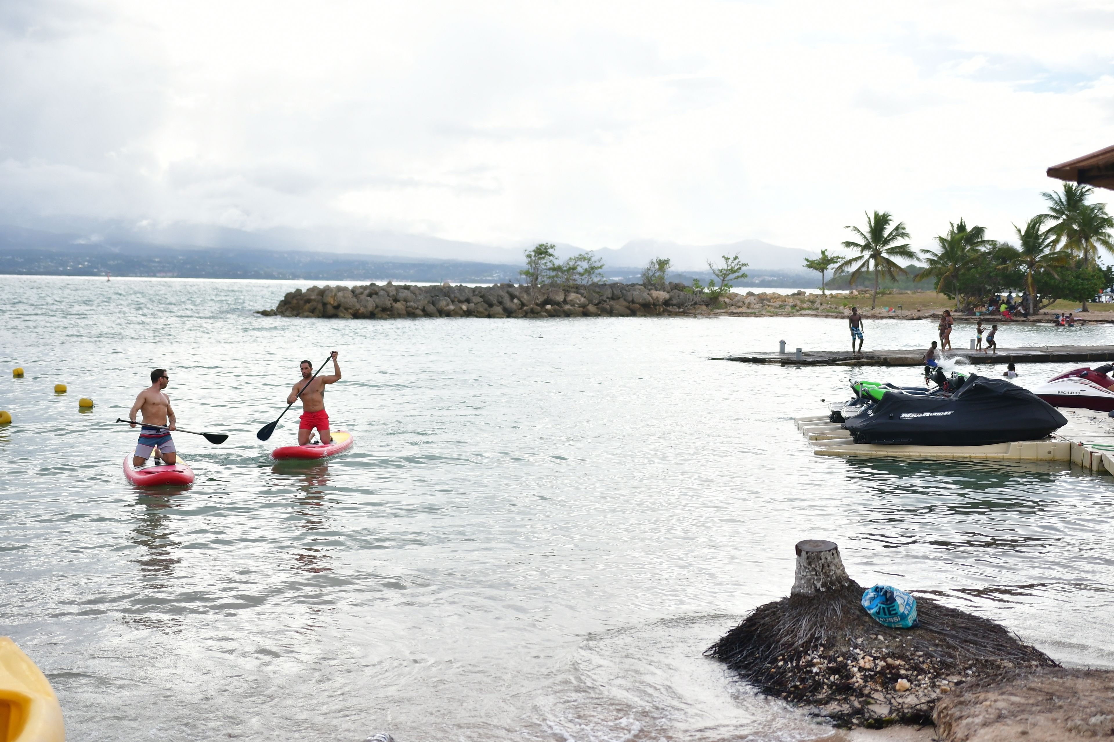 Un plan d’eau calme où l’on peut faire du paddle, du jet-ski, et où se trouve un quai avec des gens.