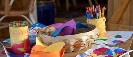 A table with a basket, a can of colorful paint, and a container of pencils.