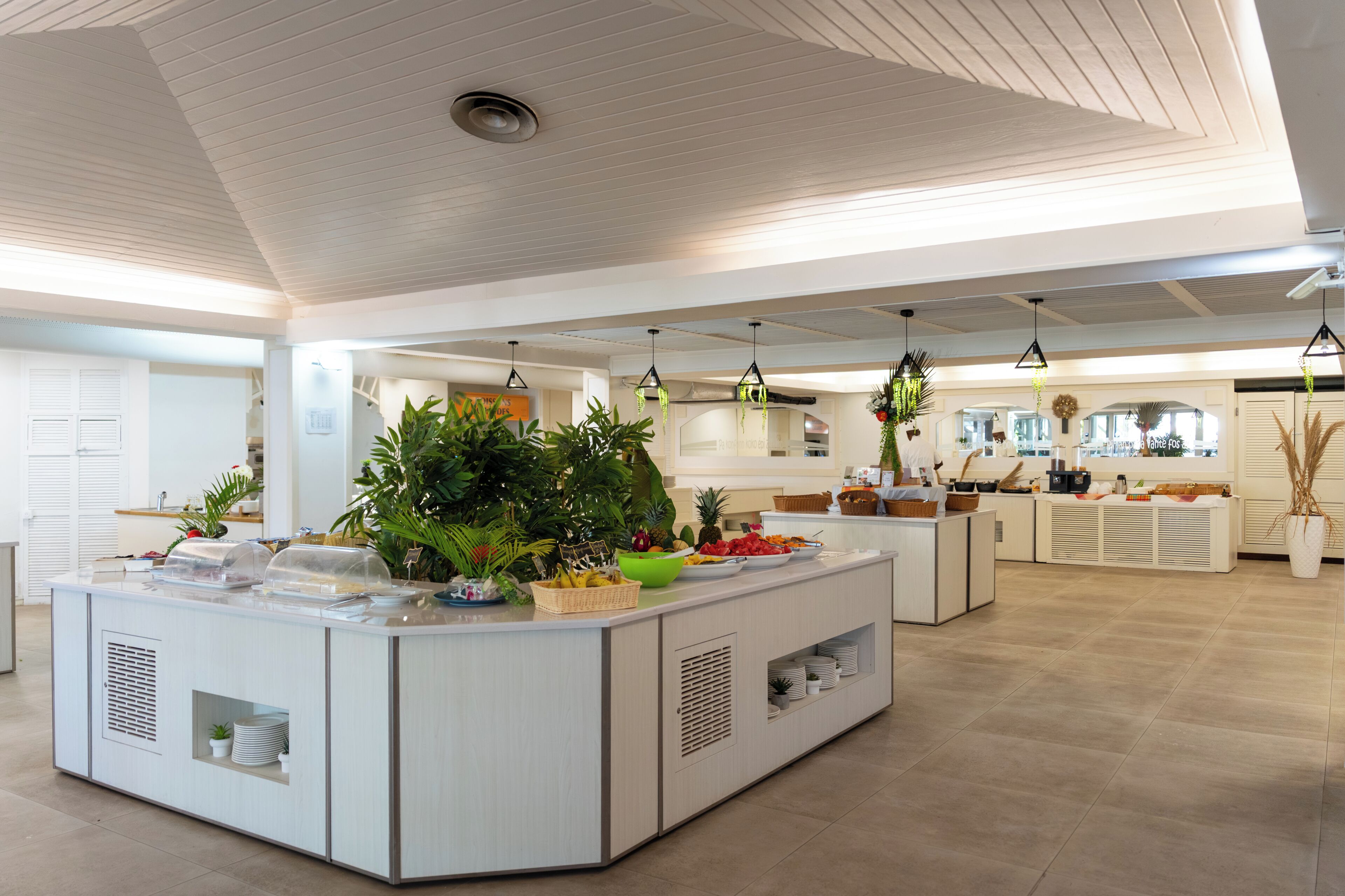 Una cocina moderna con una isla central, electrodomésticos integrados e iluminación colgante.
