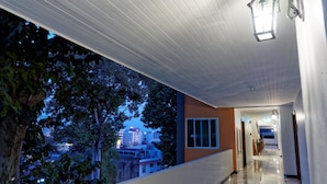 A corridor with a view of a cityscape at dusk, a modern building with a glass facade, and a hanging light fixture. - Pattaya Blue Sky (Pattaya)