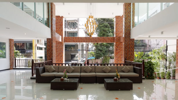 A spacious lobby with a large sofa set, a glass railing, and a view of the street outside. - Pattaya Blue Sky (Pattaya)