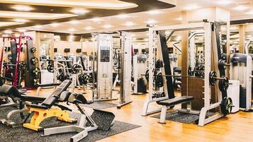 Uma academia com diversos equipamentos de exercícios, bancos e aparelhos de musculação.