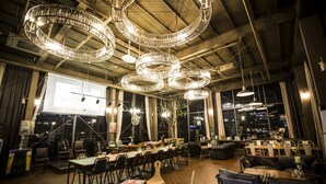 A spacious dining area with multiple tables and chairs, large windows offering city views, and ornate circular chandeliers. - Isquare Hotel (Gimhae)