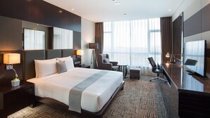 A modern hotel room with a large bed, a desk, a chair, and a television. - Isquare Hotel (Gimhae)