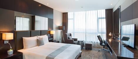 Una habitación de hotel moderna con una cama grande, un escritorio, una silla y un televisor.