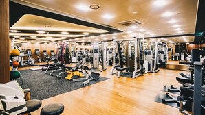A gym with various exercise equipment, wooden flooring, and a mirror wall. - Isquare Hotel (Gimhae)